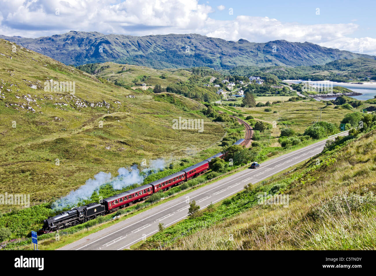 Le train à vapeur Jacobite de l'après-midi laissant Morar dans l'ouest des Highlands d'Écosse avec le sable blanc de Morar à droite Banque D'Images