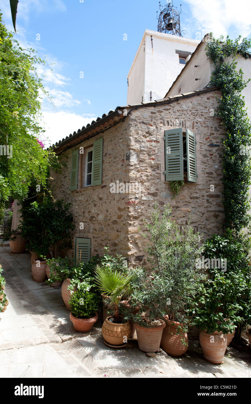 Grimaud, Var Cote d'Azur, France. Ancienne maison de pierre dans la rue étroite avec des volets verts et des plantes décoratives Banque D'Images