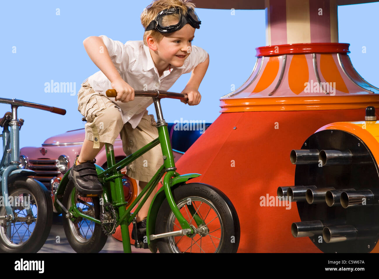 Allemagne, Landshut, little boy (4-5) carrousel équestre vélo, smiling Banque D'Images