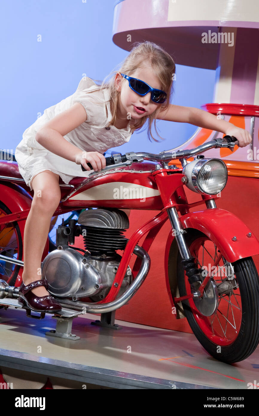 Allemagne, Landshut , little girl (4-5) carrousel équestre vélo, smiling Banque D'Images
