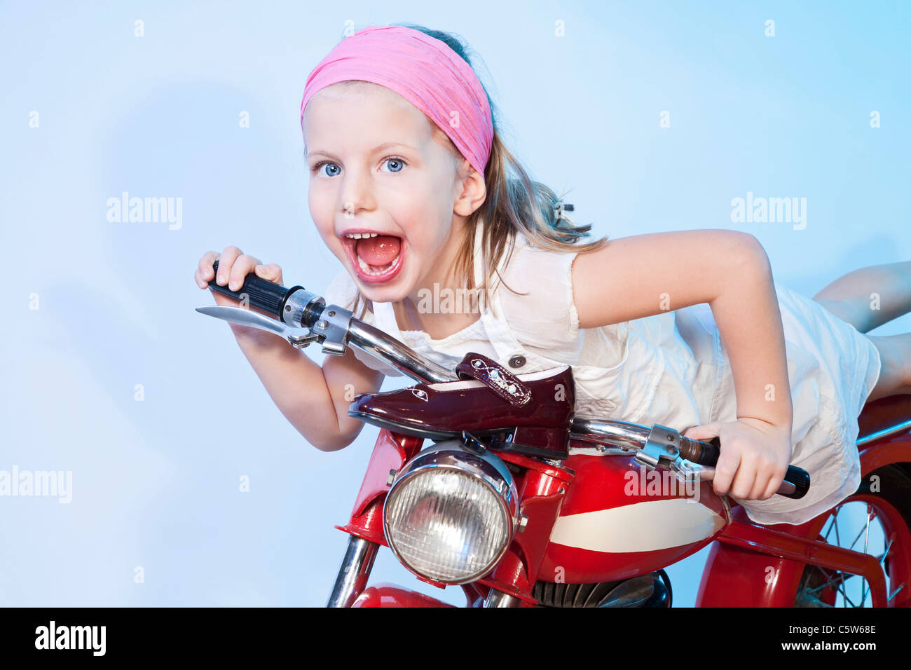 Allemagne, Landshut , little girl (4-5) carrousel équestre vélo, smiling Banque D'Images