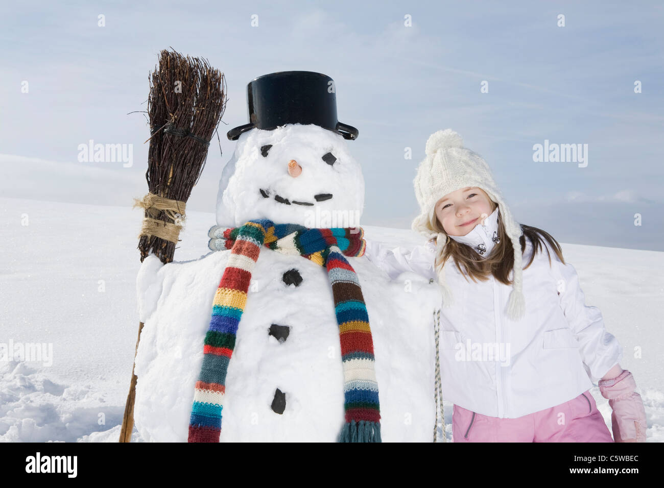 Germany, Bavaria, Munich, Girl (8-9) standing next to snowman, portrait Banque D'Images