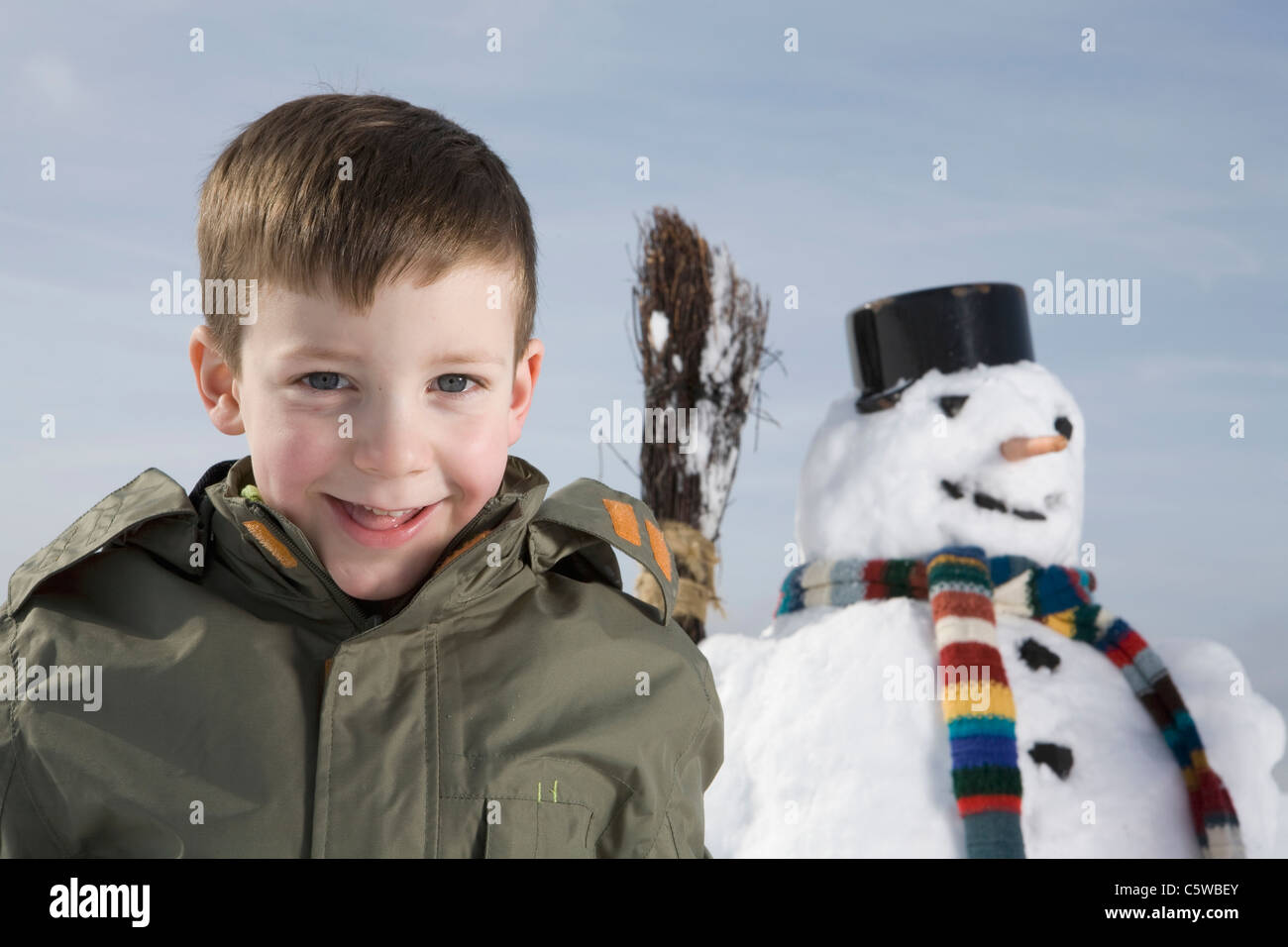 Germany, Bavaria, Munich, Boy (8-9) smiling, bonhomme de neige en arrière-plan Banque D'Images