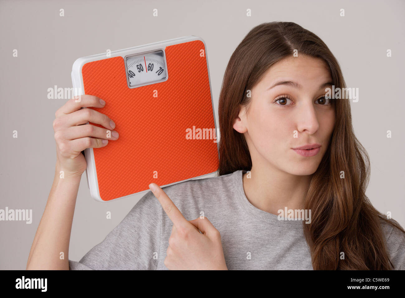 Jeune femme (16-17) holding Balances, pointant avec le doigt Banque D'Images