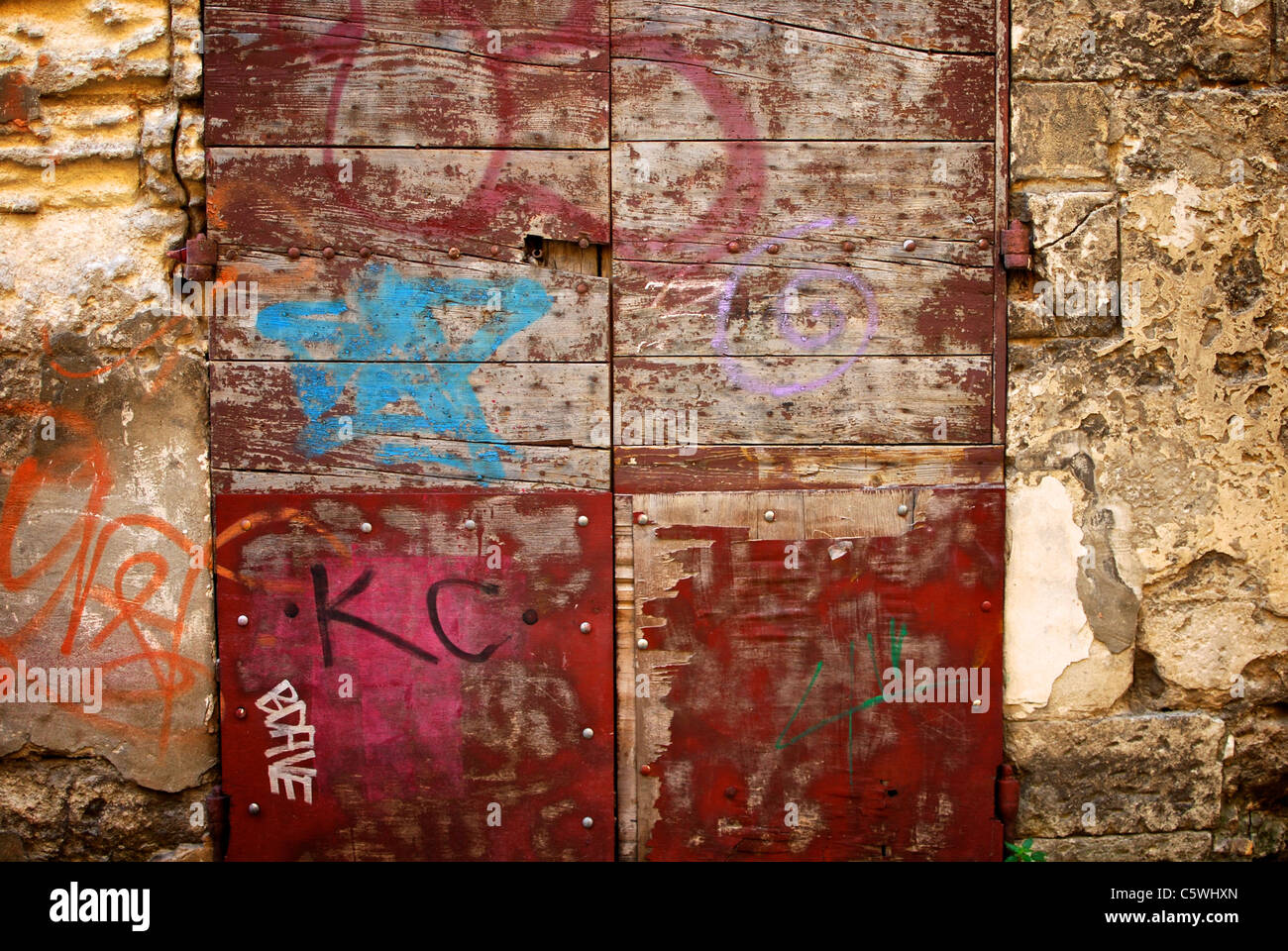 L'écaillage de la peinture, l'effritement de la maçonnerie et des graffitis dans ce détail d'une maison face à Arles, France. Banque D'Images