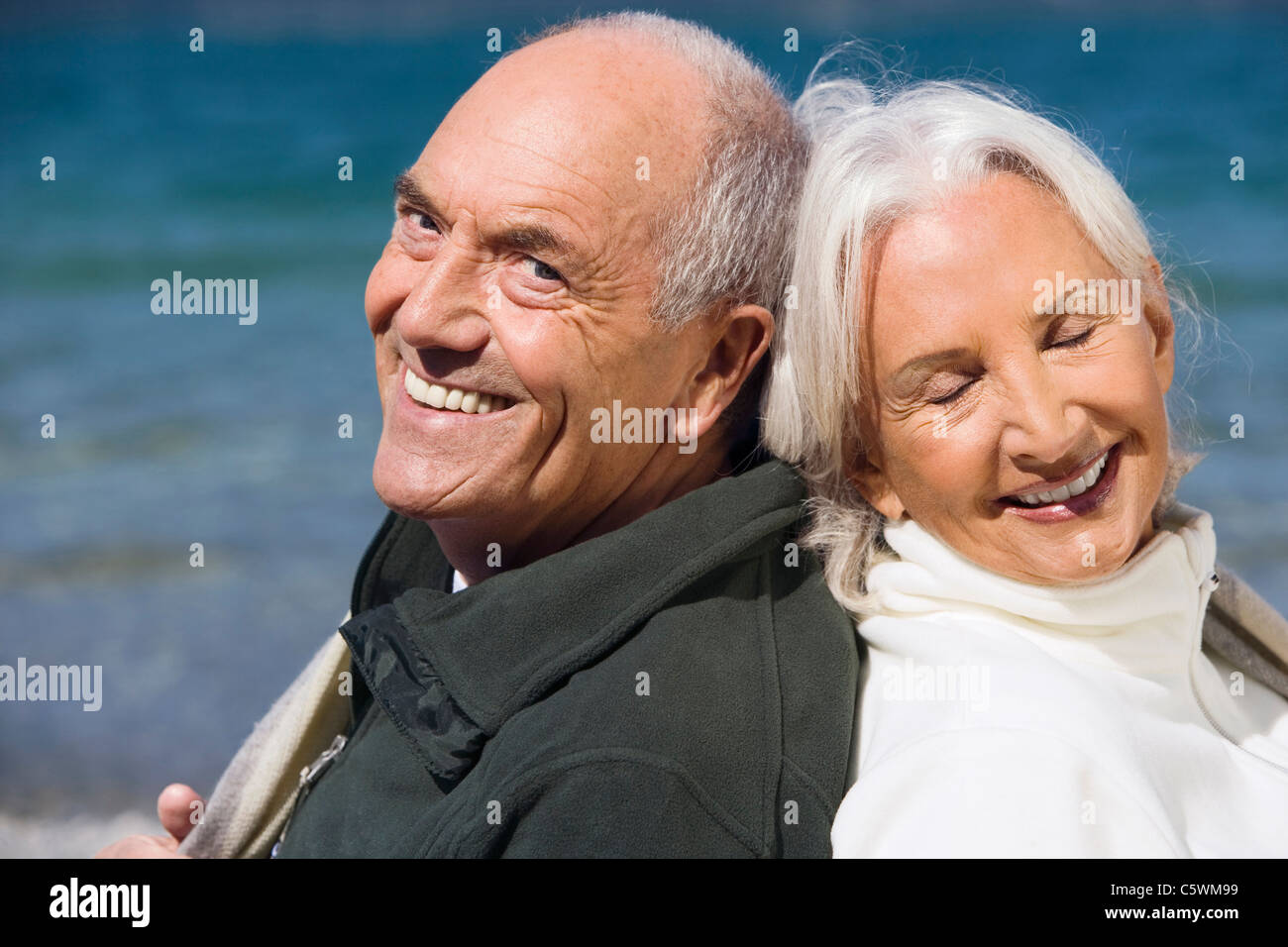 Germany, Bavaria, Senior couple relaxing on lakeshore, dos à dos, Close up, portrait Banque D'Images