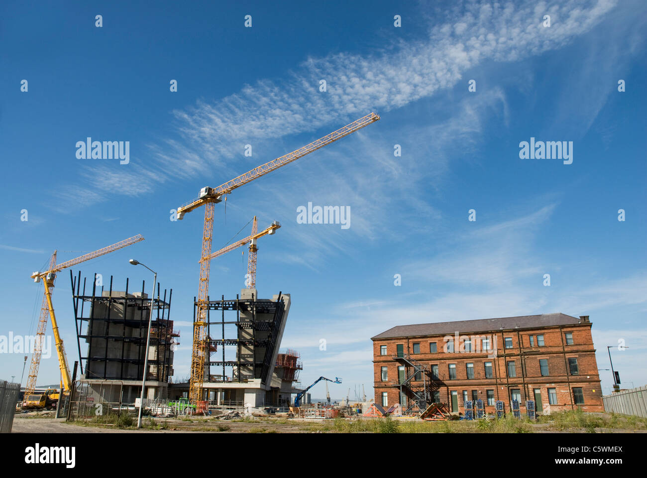 Au cours de la construction du nouveau musée du Titanic de Belfast. Le bureau de dessin en brique rouge original peut être vu à droite. Banque D'Images