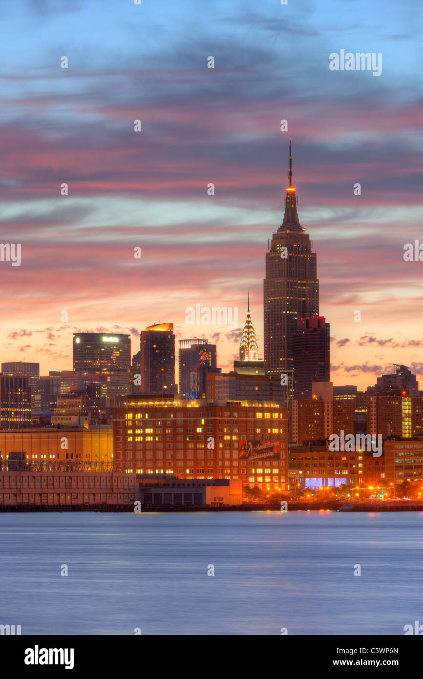 Le ciel commence à s'éclaircir et refléter des nuages couleur sunrise sur l'Empire State Building et d'autres bâtiments de la midtown Manhattan skyline. Banque D'Images