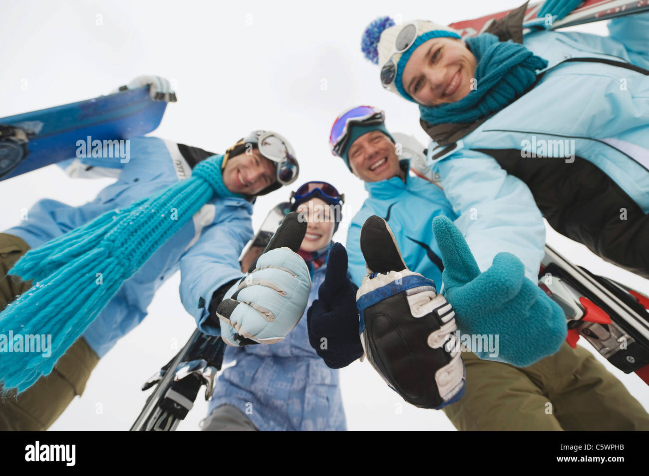L'Italie, le Tyrol du Sud, quatre personnes dans des vêtements d'hiver, Thumbs up, low angle view Banque D'Images