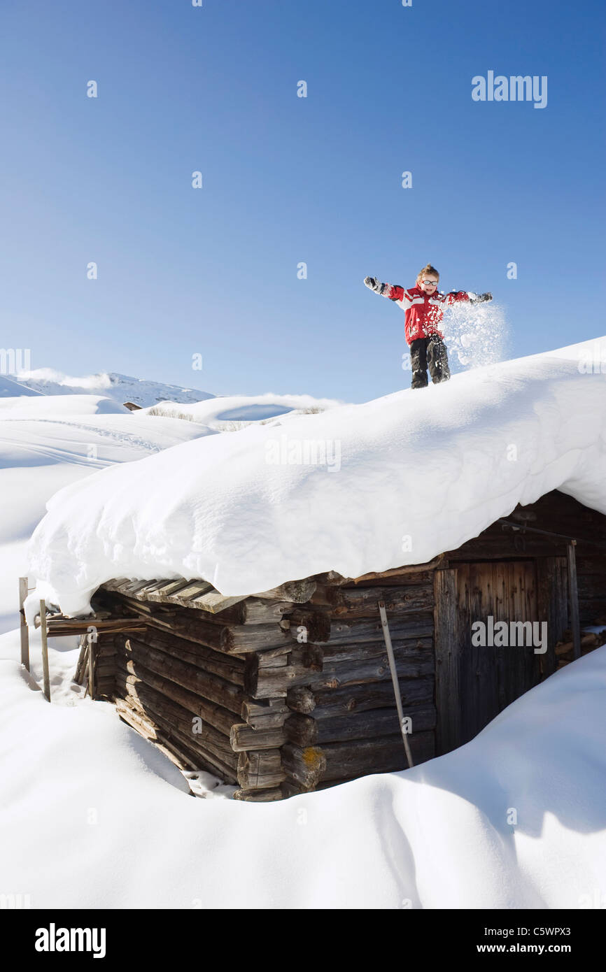 Germany, Berlin, Young) debout sur le toit couvert de neige de log cabin Banque D'Images