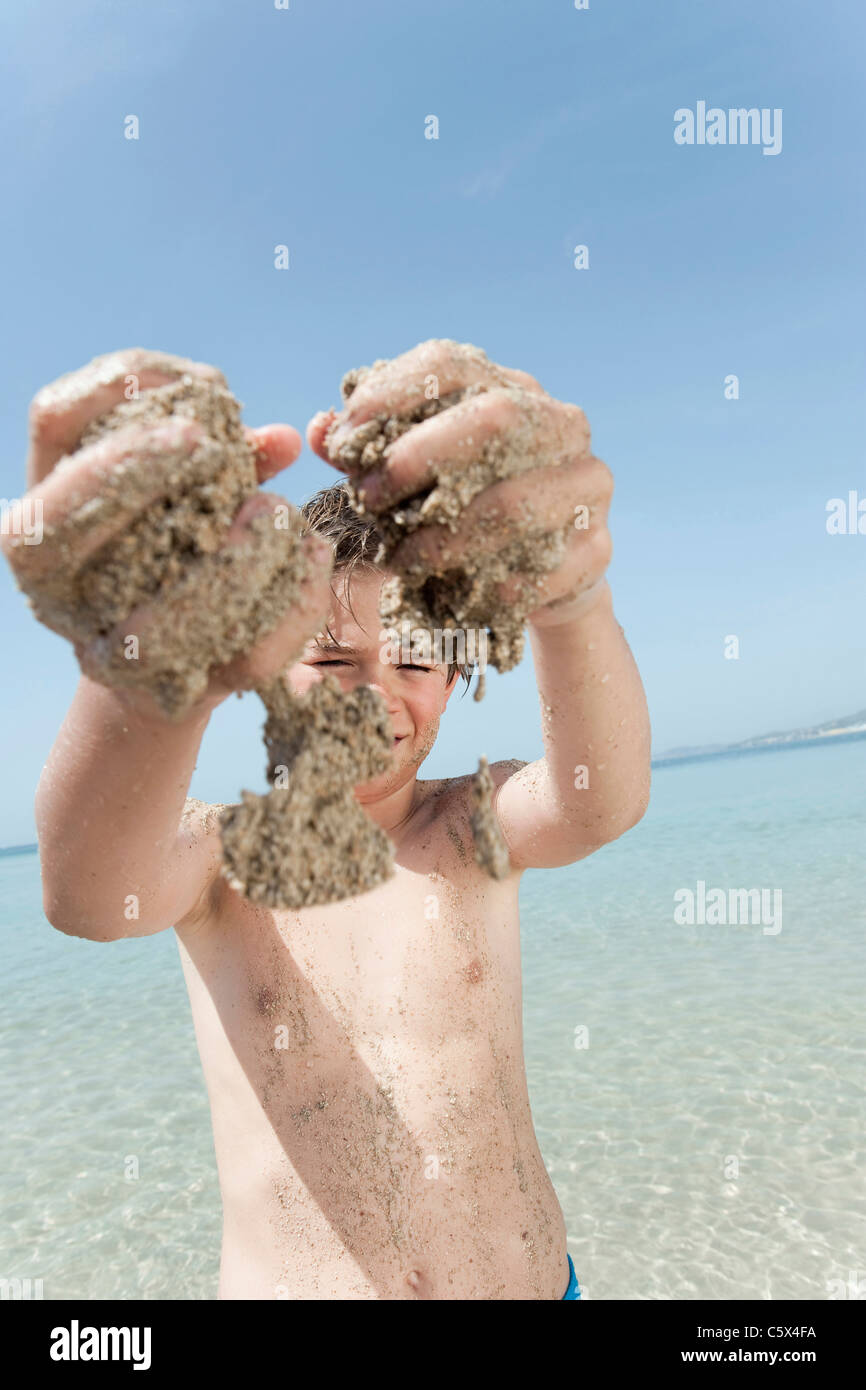 Espagne, Majorque, Boy (8-9) avec les mains de sable à jouer sur la plage Banque D'Images