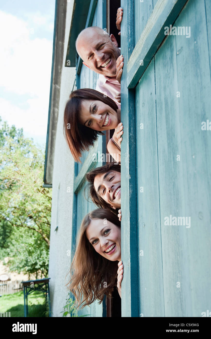 Germany, Bavaria, quatre personnes debout à côté de porte de grange, smiling, portrait Banque D'Images