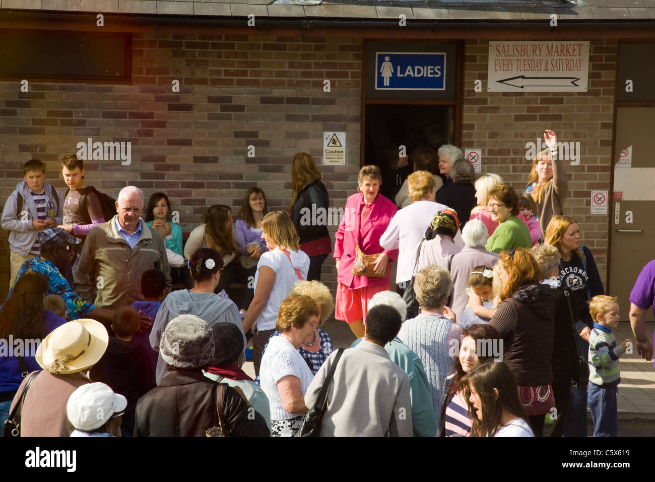 Foules et longue file d'attente à l'extérieur d'un chers toilettes dans une station service Banque D'Images