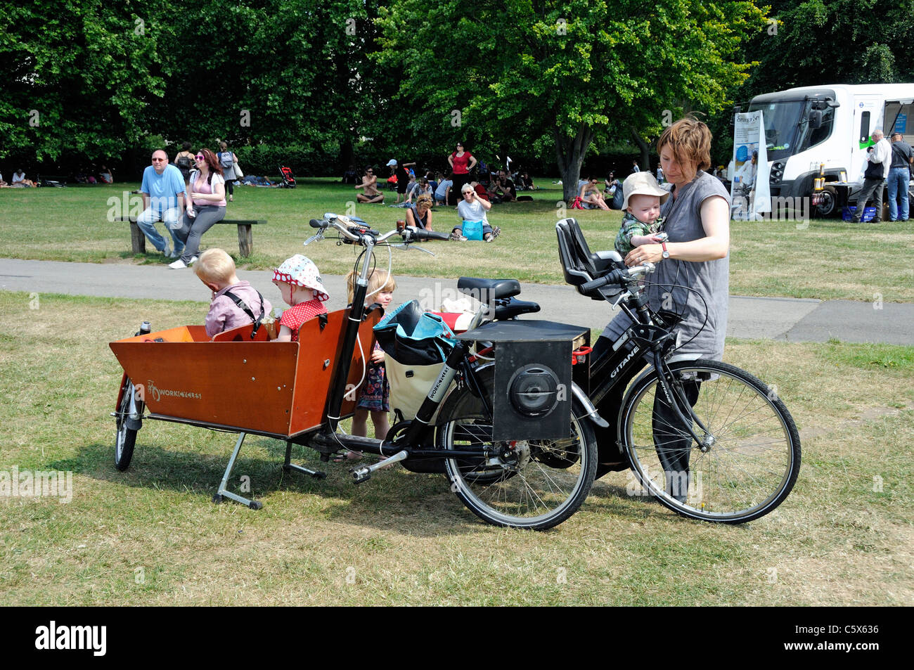 Femme avec un vélo et quatre petits enfants dans une remorque deux workcycles à Camden Londres maintenant juste vert England UK Banque D'Images