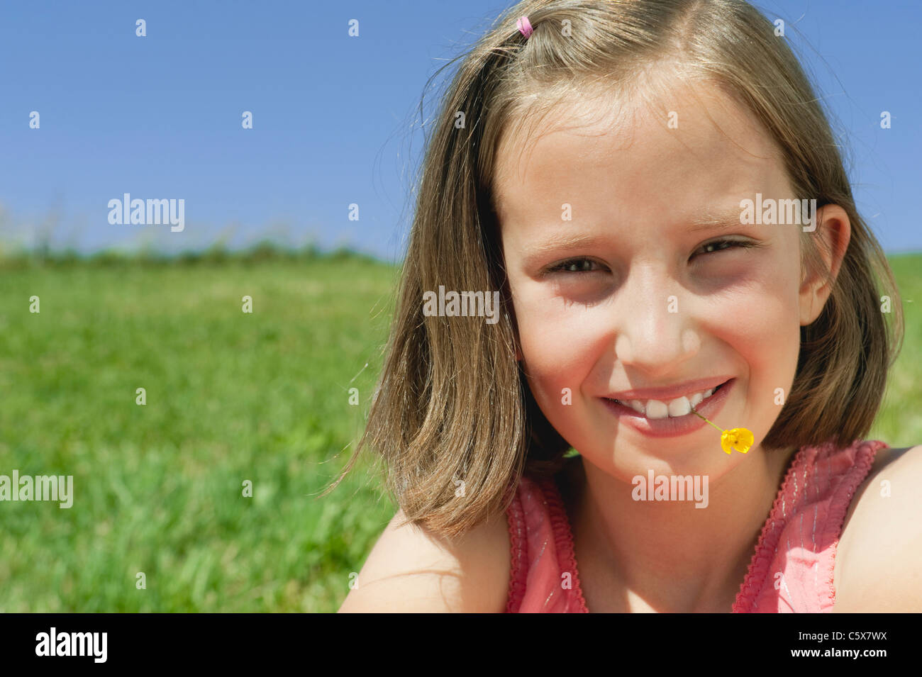 Germany, Berlin, Girl (10-11) avec une fleur dans la bouche, portrait, close-up Banque D'Images