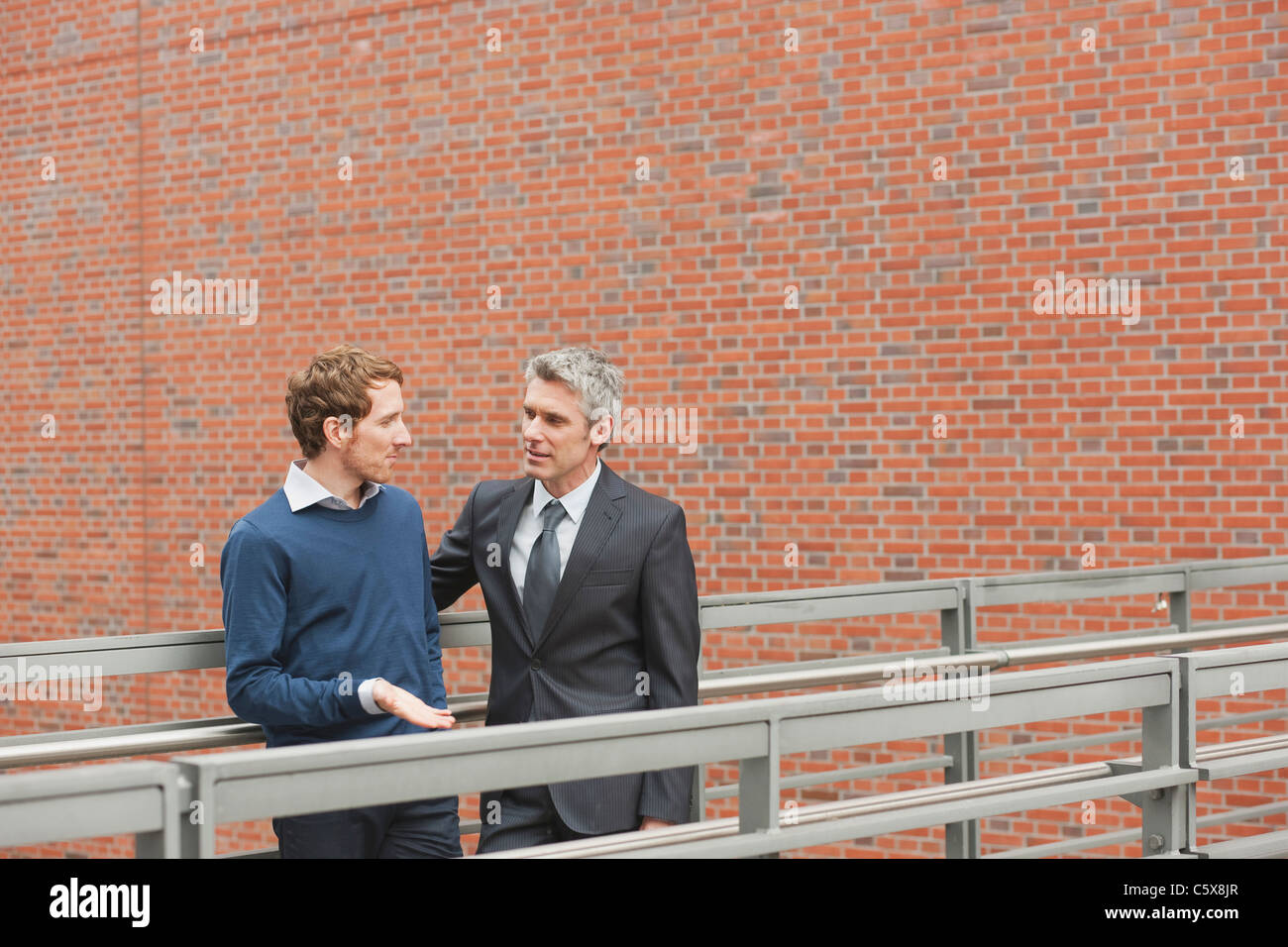 Allemagne, Hambourg, deux hommes d'parler devant un mur de briques Banque D'Images