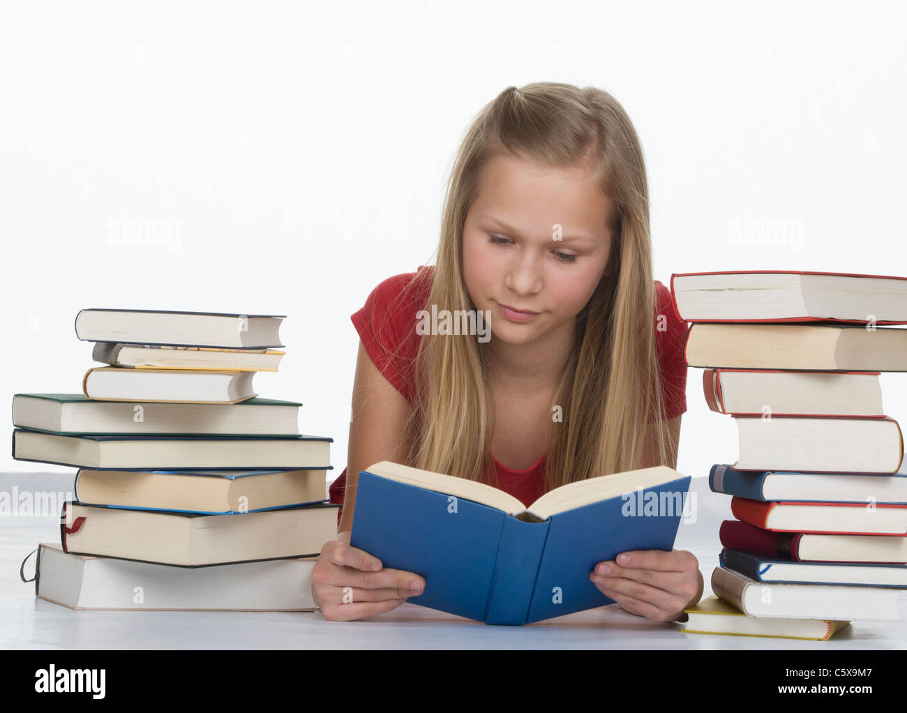 Girl reading book en plus de pile de livres contre fond blanc Banque D'Images