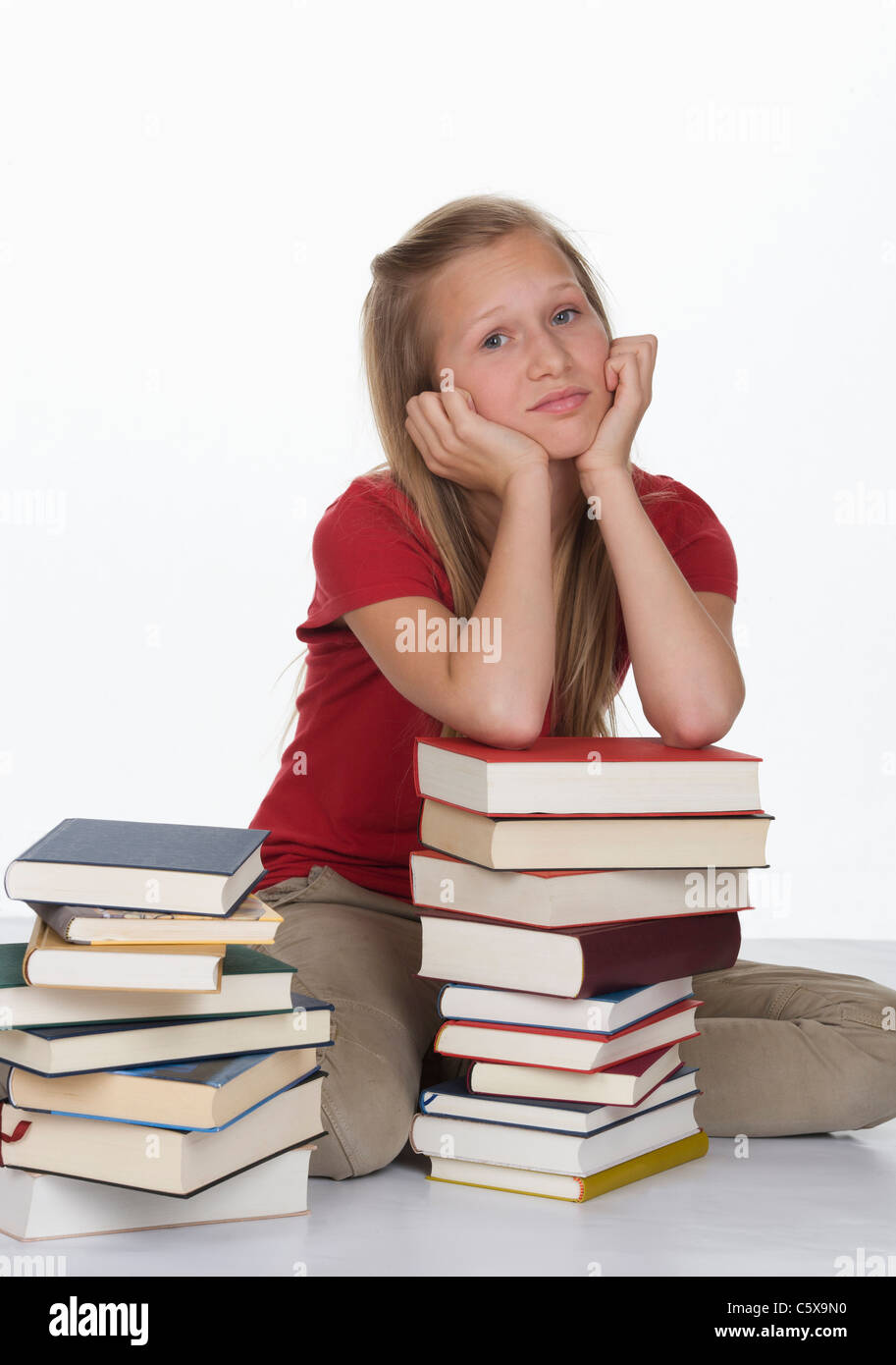 Fille assise à côté pile de livres contre fond blanc Banque D'Images