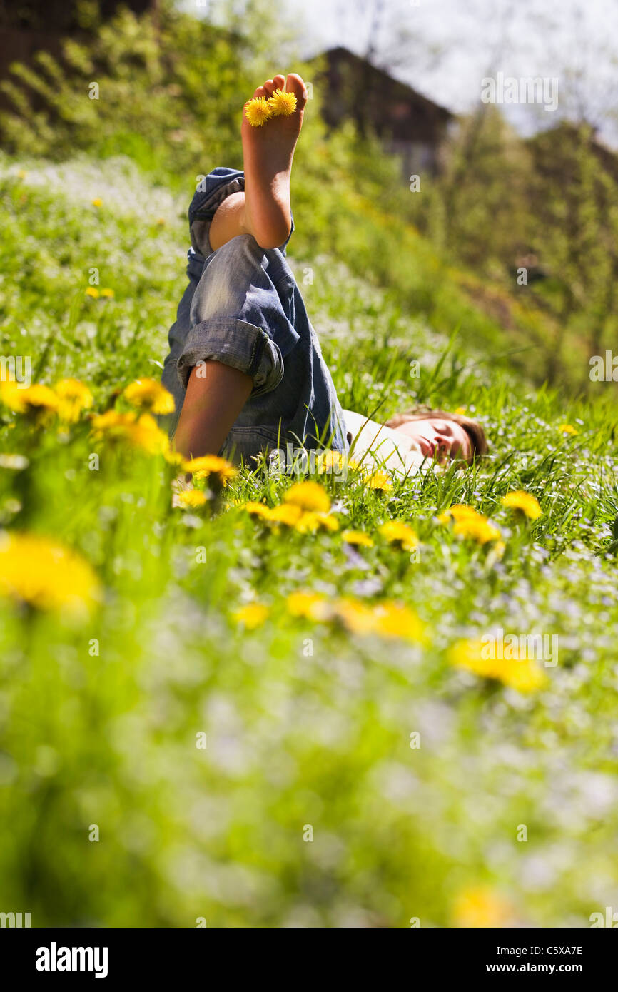 Young man relaxing in prairie, fleurs de pissenlit entre les orteils Banque D'Images