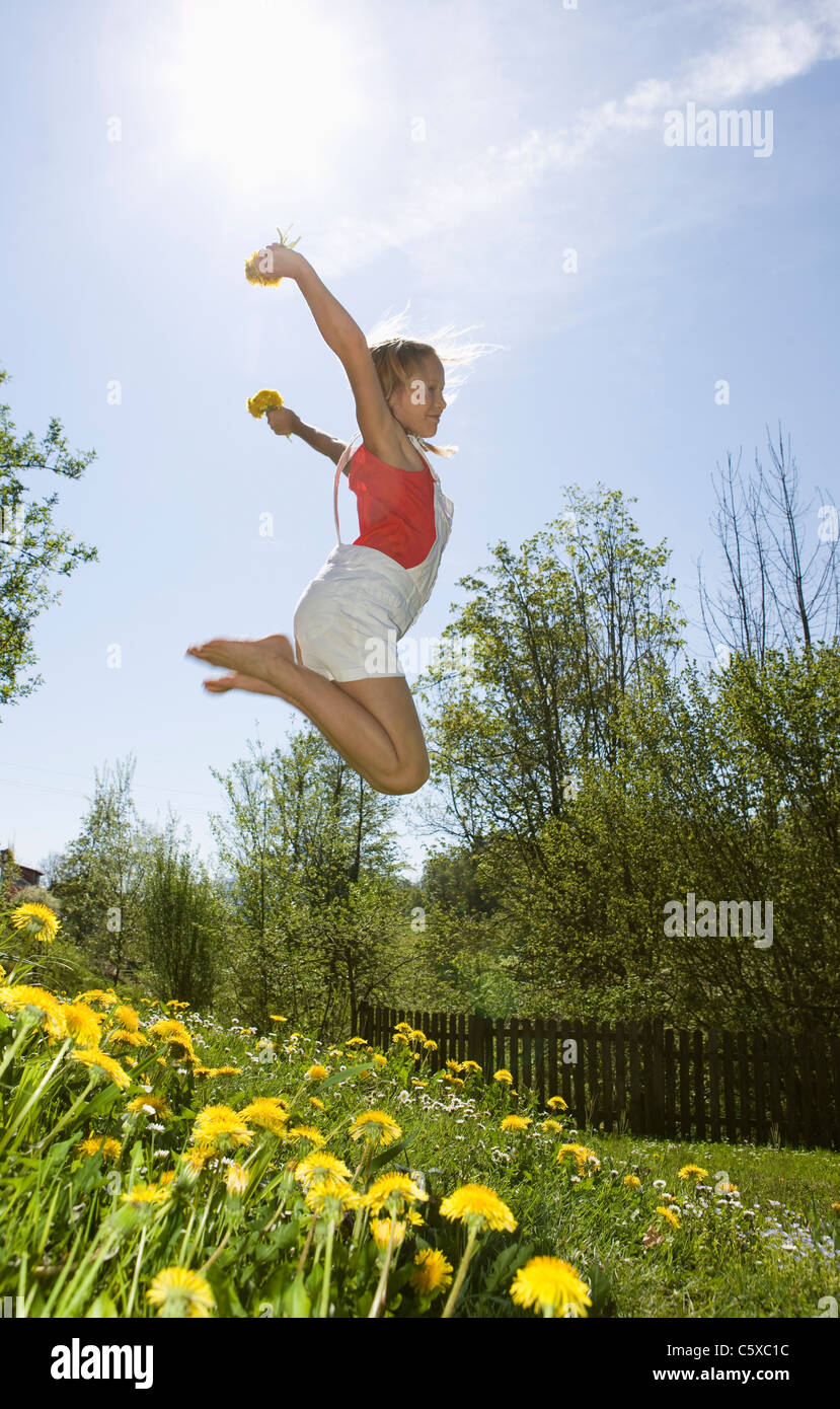 L'Autriche, Salzkammergut, girl (10-11) jumping in jardin, vue latérale Banque D'Images
