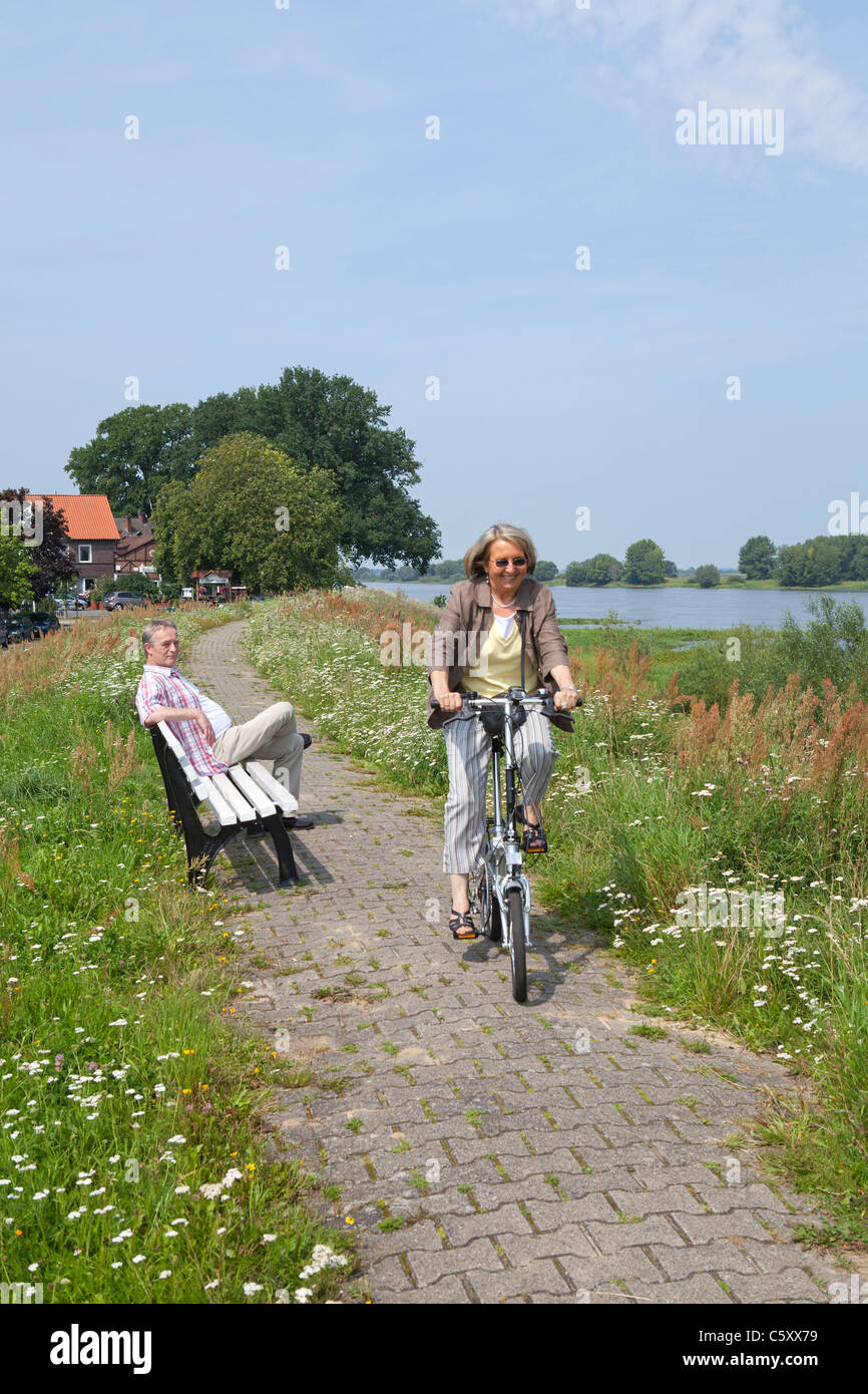 Femme à vélo sur la digue à côté d'Elbe près de Wussegel près de Hitzacker, réserve naturelle Elbufer-Drawehn, Basse-Saxe, Allemagne Banque D'Images