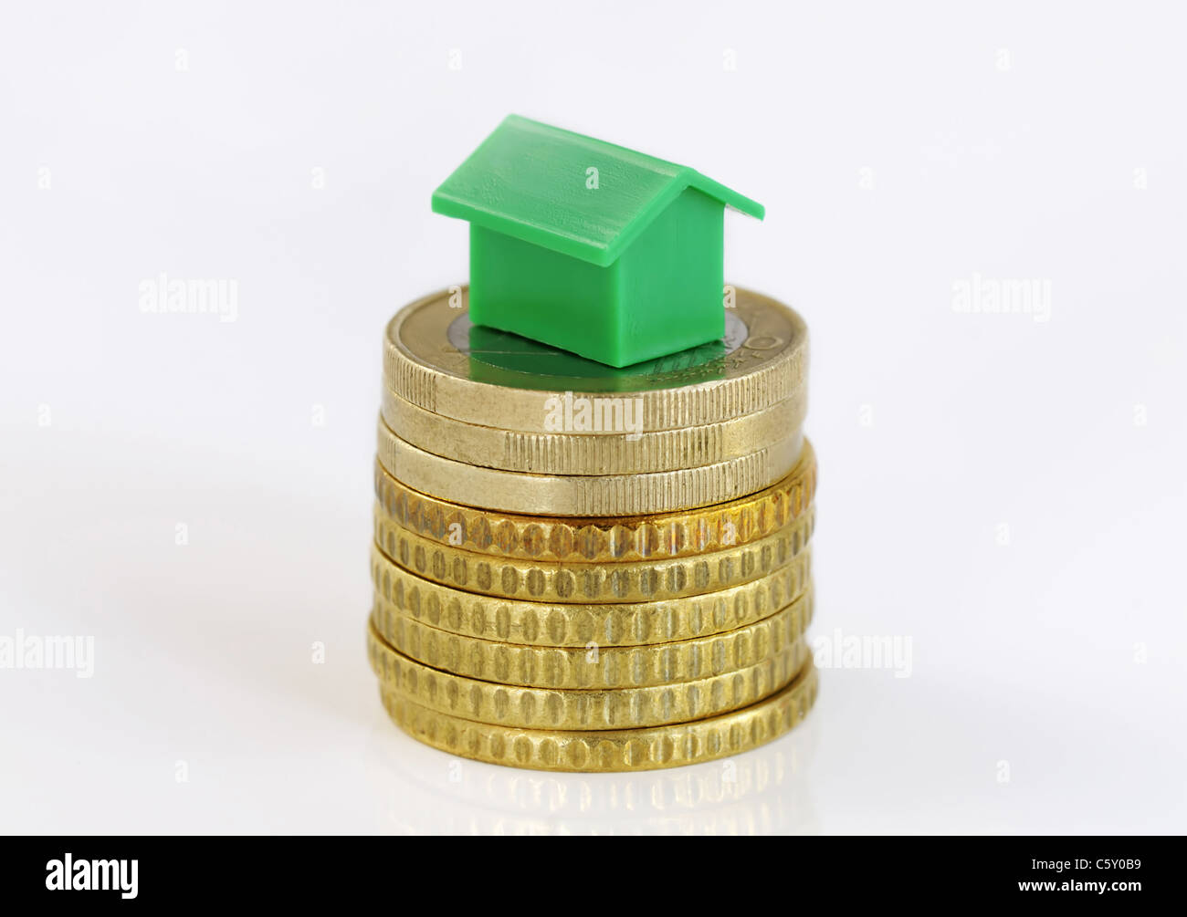 Close-up of a green model house sur une pile de pièces isolated on white Banque D'Images