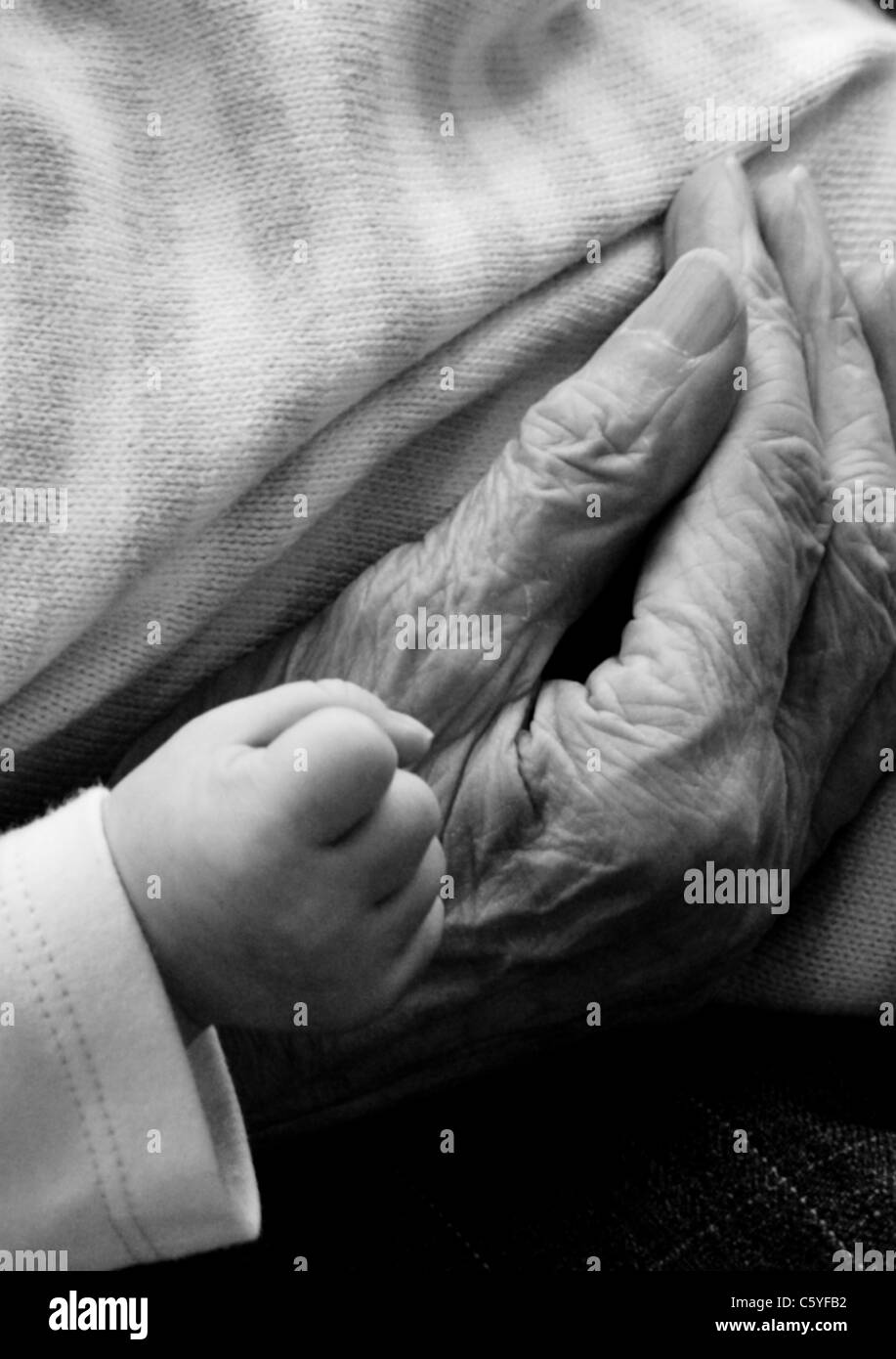Une main serrée du bébé à côté d'une vieille femme ridée de part en noir et blanc Banque D'Images