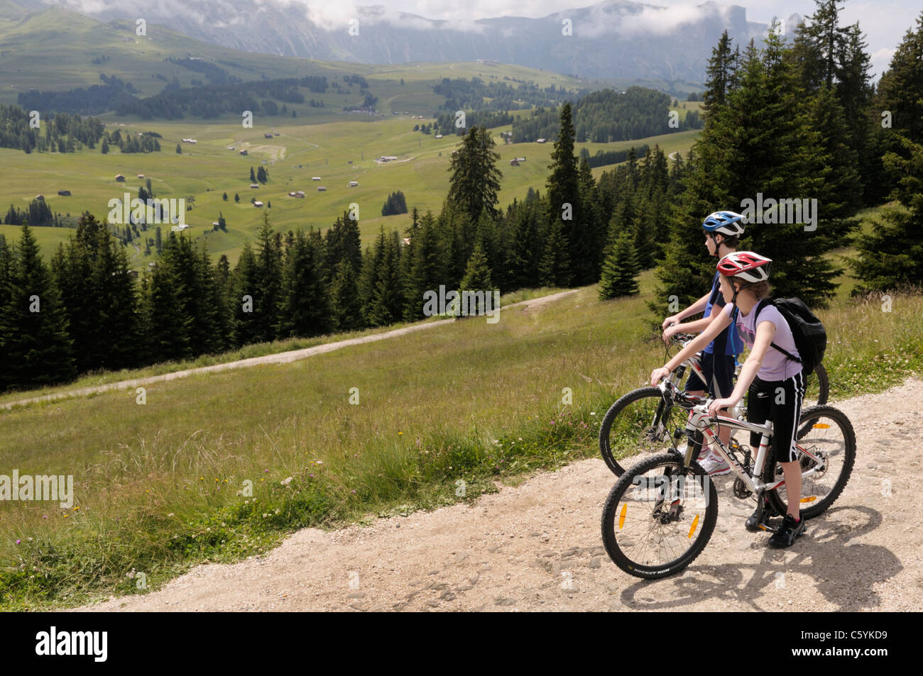 Garçon et fille, 14 et 12, sur des vélos sur l'Alpe di Siusi, près de Val Gardena, Italie. Banque D'Images