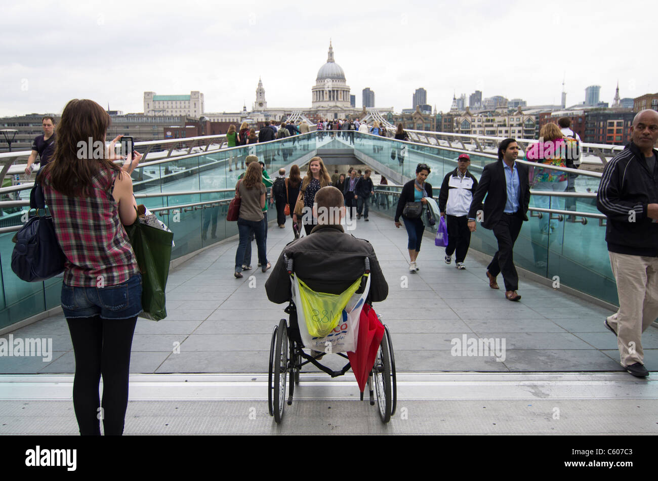Homme handicapé en fauteuil roulant mendier dans le Millennium Bridge sur Southbank avec St Pauls dans l'arrière-plan Banque D'Images