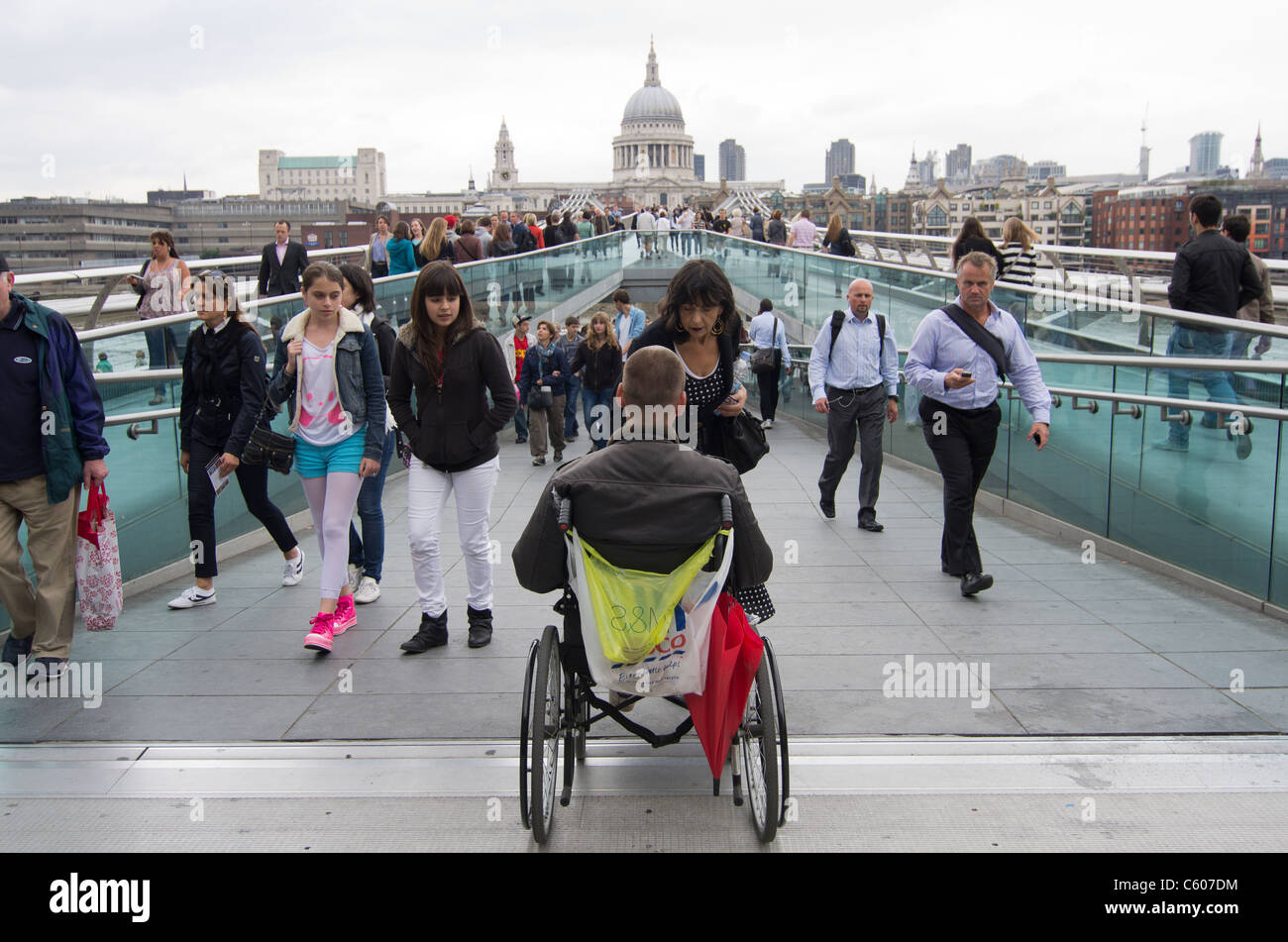 Homme handicapé en fauteuil roulant mendier dans le Millennium Bridge sur Southbank avec St Pauls dans l'arrière-plan Banque D'Images