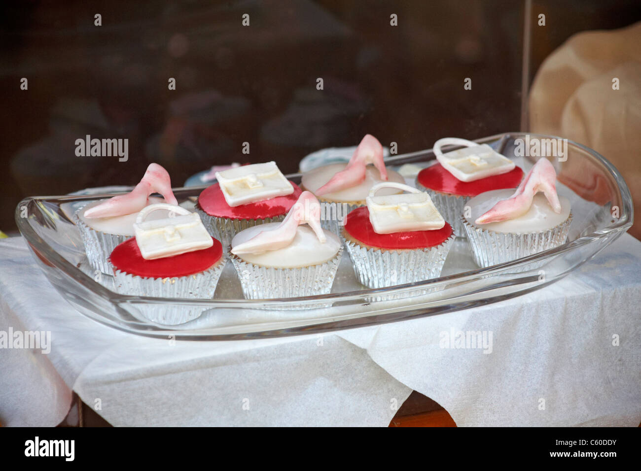 De plaque glacé rouge et blanc cup cakes cupcakes décorée avec des sacs à main et chaussures sur la plaque en boutique, Moreton in Marsh, Cotswolds Banque D'Images