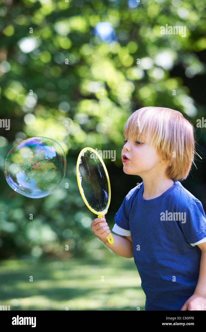 Boy blowing bubble surdimensionnés in backyard Banque D'Images