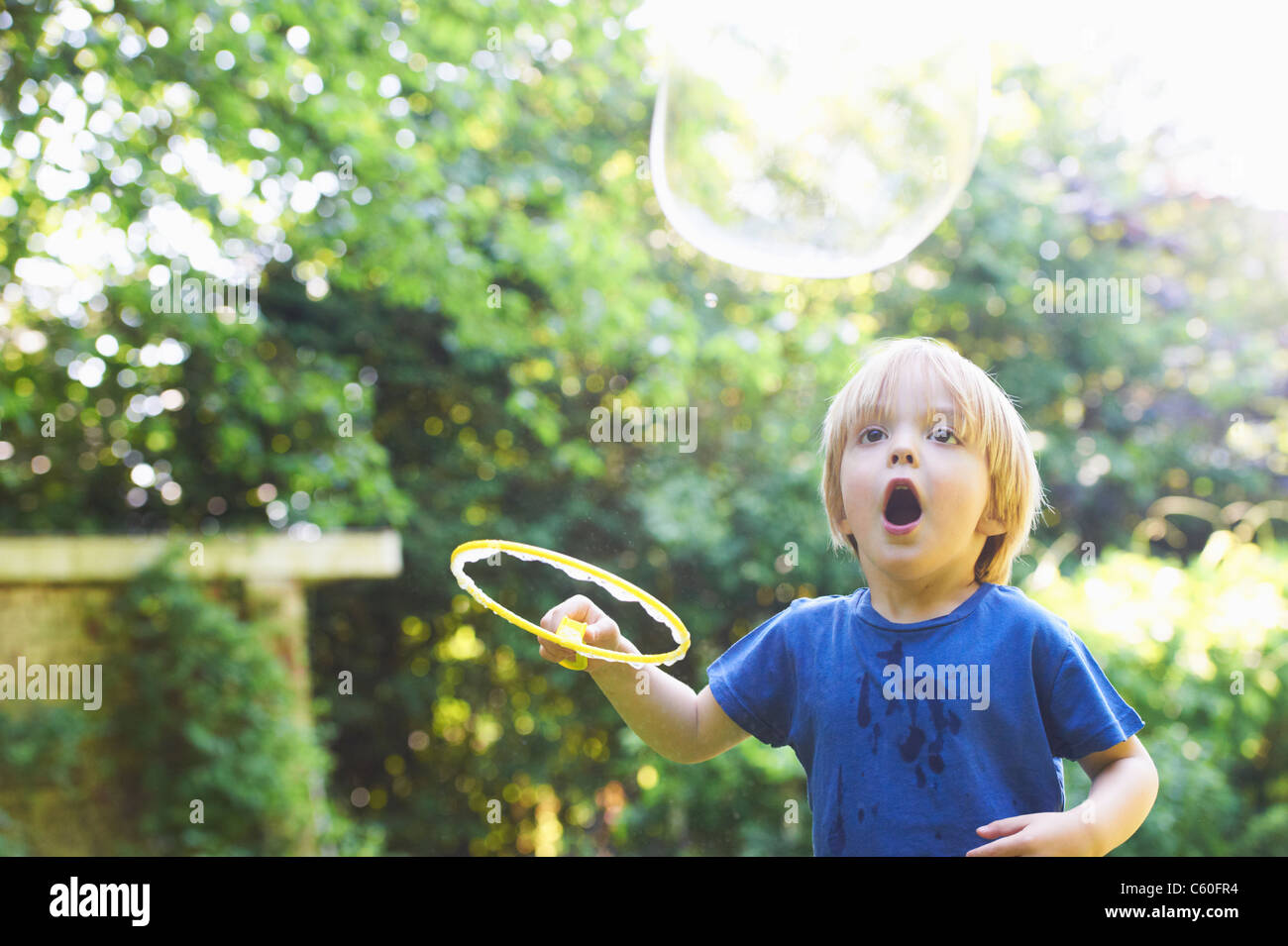Boy making bulle surdimensionné in backyard Banque D'Images