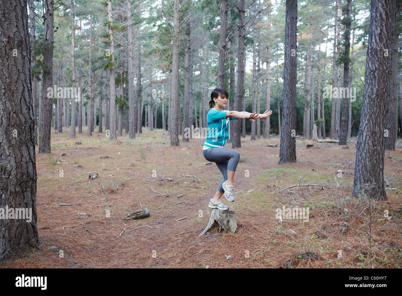 Woman balancing sur moignon en forêt Banque D'Images