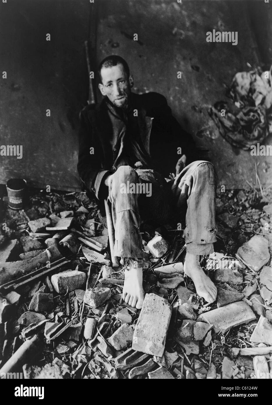 Le Français prisonnier à Nordhausen concentration camp au milieu des décombres de la prison en attente d'une ambulance pour l'emmener à l'hôpital après la libération par l'armée américaine d'abord le 11 avril 1945. Banque D'Images