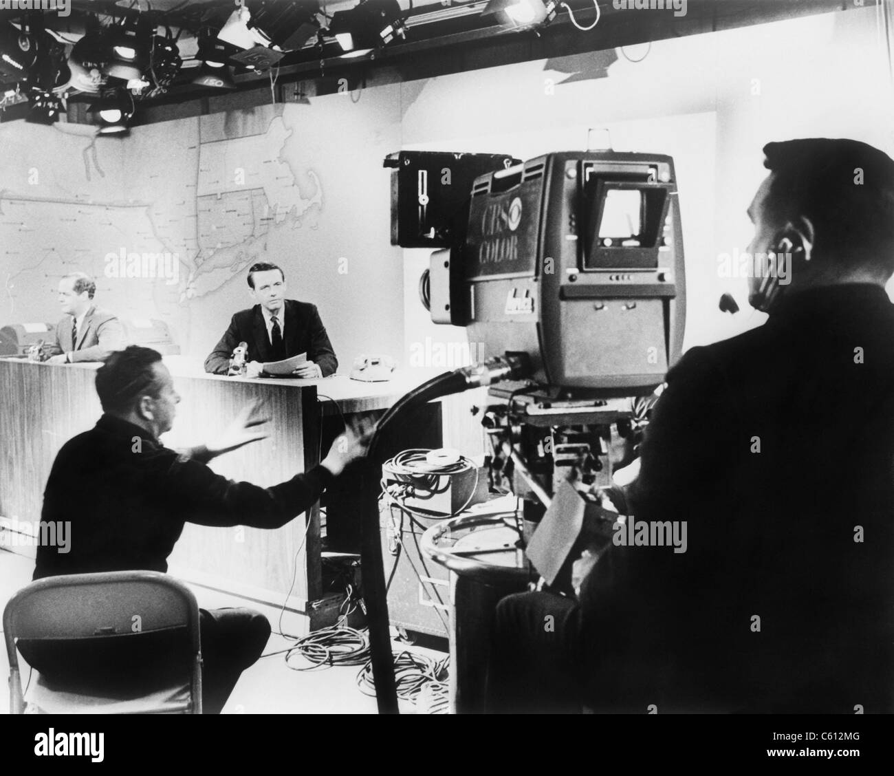 Sous sex studio lights, un présentateur de nouvelles de CBS effectue sous le directeur de son producteur (assis entre l'ancrage et l'appareil photo), pour une caméra de télévision couleur en 1967. Banque D'Images