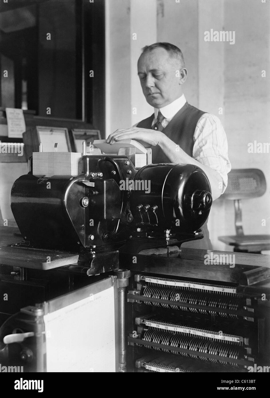Man loading cartes perforées dans un tabulating machine utilisée dans le recensement des États-Unis de 1920. C'est un prédécesseur de calculateurs électroniques, et travaillé par la lecture des cartes perforées mécaniquement avec l'information codée. Banque D'Images