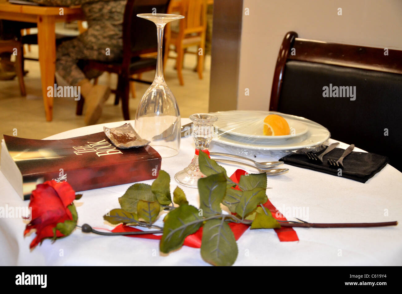 Un joint Marine anonyme en l'honneur d'un des coéquipiers en plaçant son trident sur la Bible à l'honneur des soldats' Table dans une salle à manger en Afghanistan. Les soldats tombés la table est une tradition militaire de longue date de l'établissement d'un lieu unique et complète la mise en mémoire des soldats qui ont disparu ou ont été tués au combat. Banque D'Images