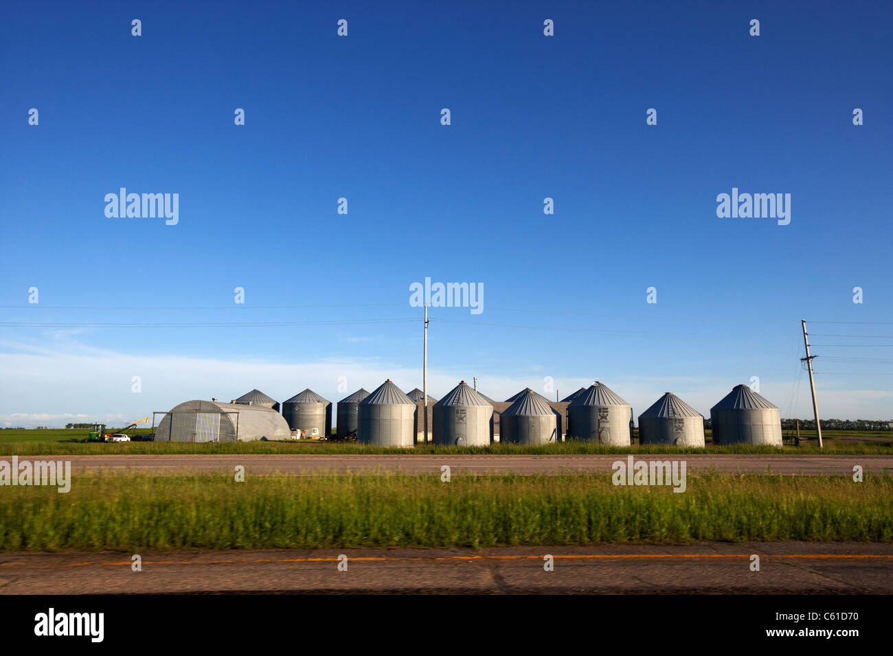 Cours de conduite les silos à grains sur les terres agricoles ouvertes du Dakota du Nord, USA Banque D'Images