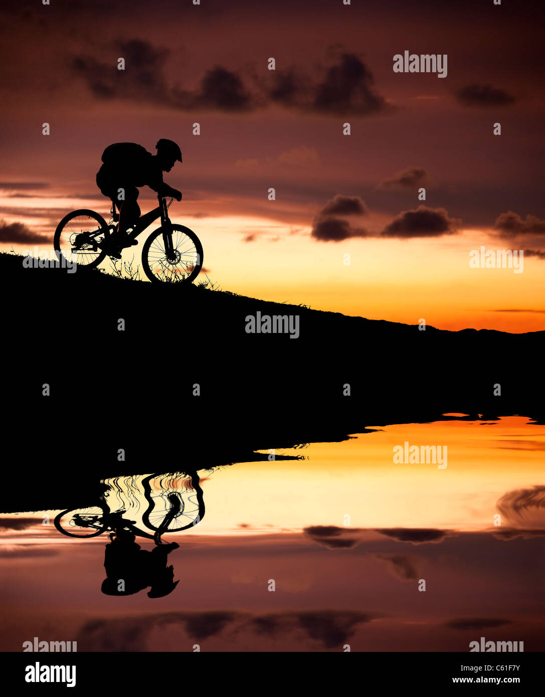 Silhouette de vélo de montagne avec la réflexion et le coucher du soleil Banque D'Images