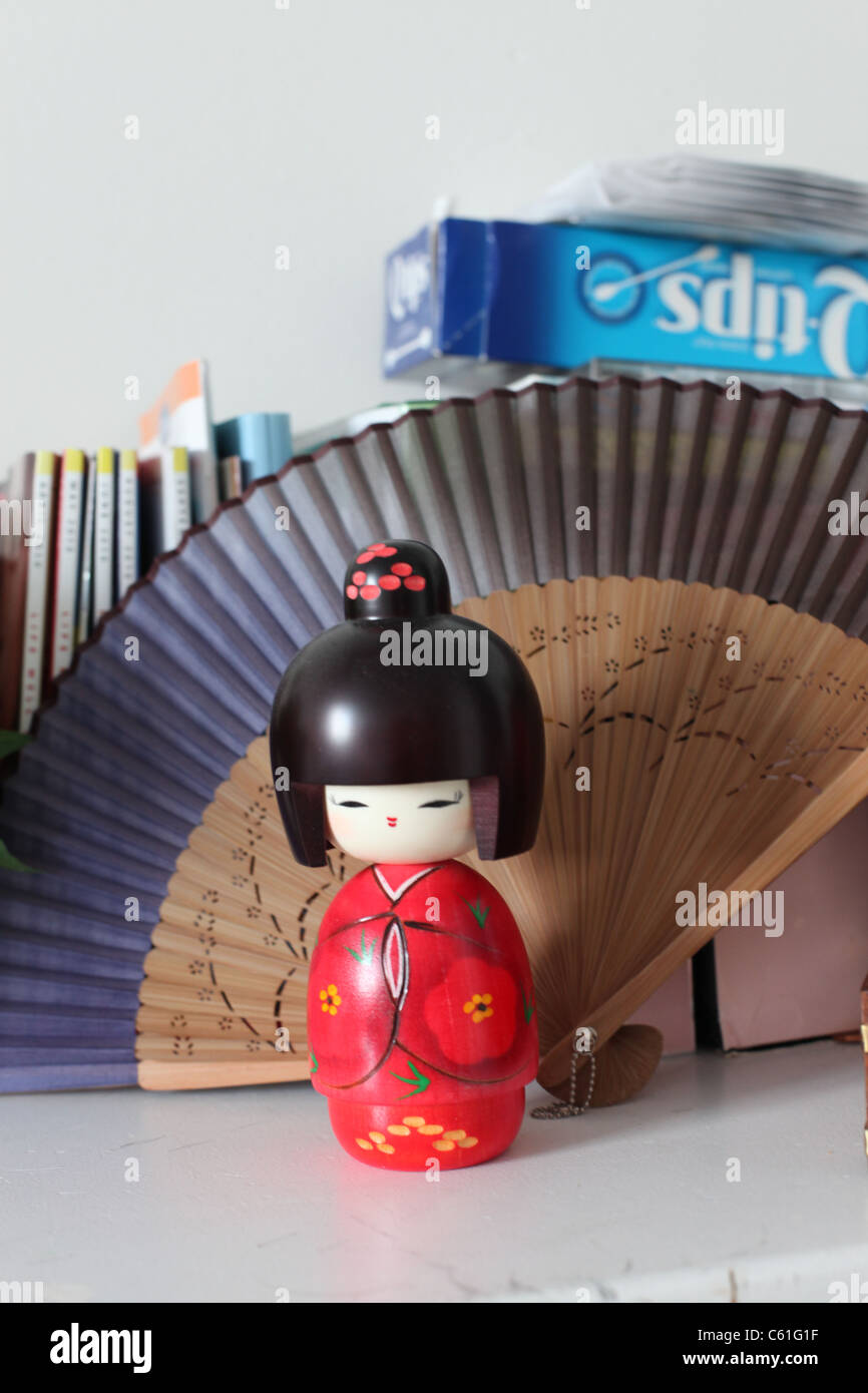 Libre d'une poupée japonaise rouge portant des kimono traditionnel avec un ventilateur de pliage de papier dans l'arrière-plan 2011 Banque D'Images