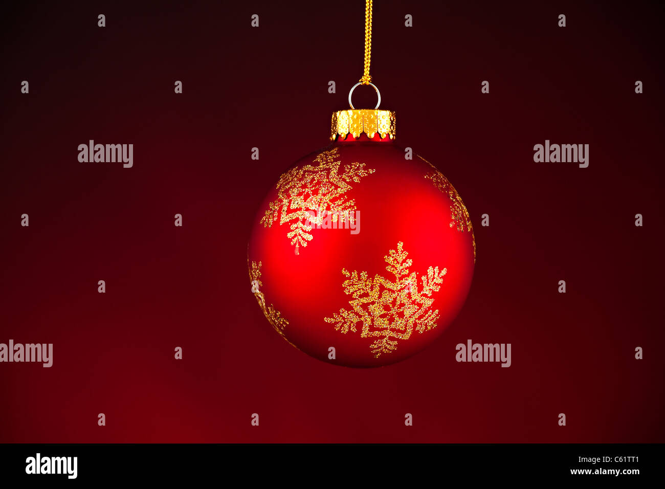 Un ornement d'arbre de Noël rouge isolés contre un fond rouge foncé. Banque D'Images