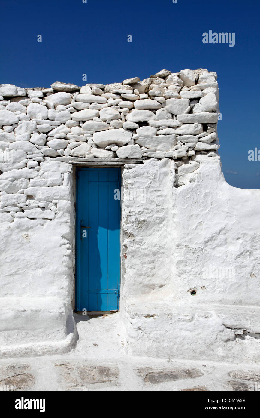 Porte en bois bleu étroit dans un mur en brique blanche. Vieille ville de Mykonos, Grèce, Europe. Banque D'Images