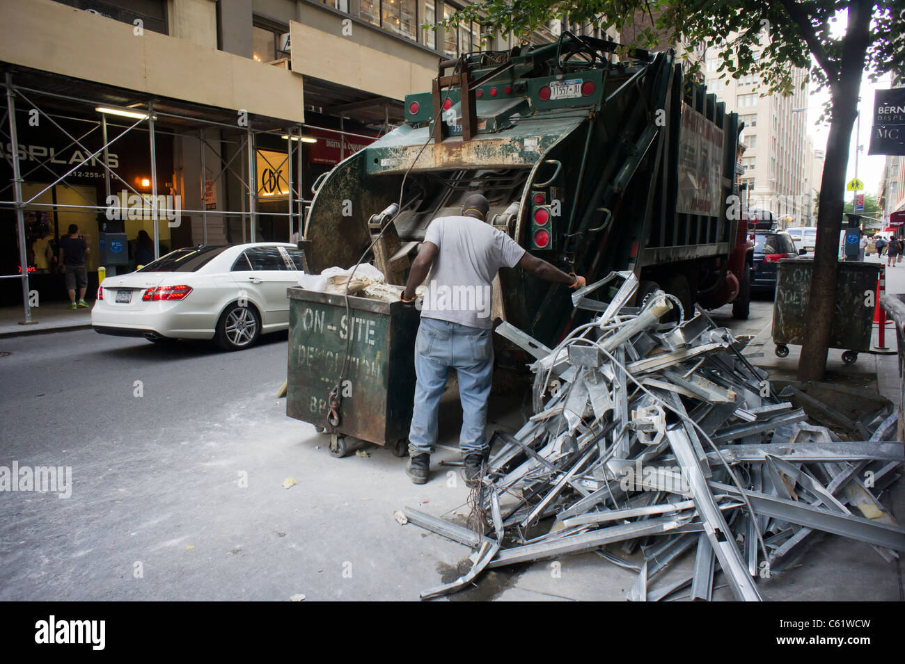Un travailleur charge un camion poubelle avec des débris de construction à des fins de recyclage dans le quartier de Chelsea à New York Banque D'Images