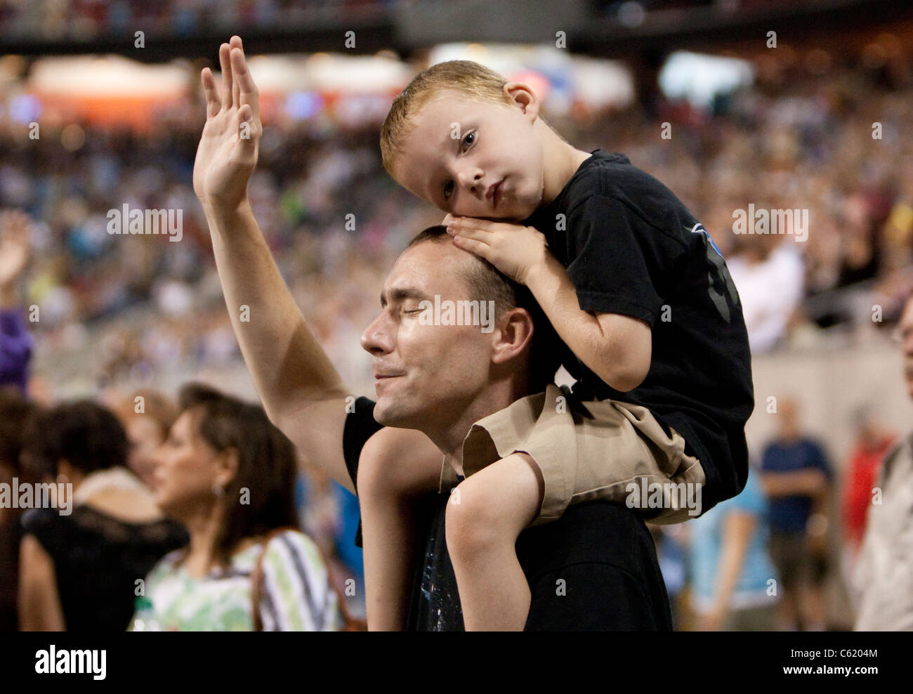Tenir la main de père blanc et ferme les yeux tout en priant avec son jeune fils sur ses épaules à la foi chrétienne de l'événement de prière Banque D'Images