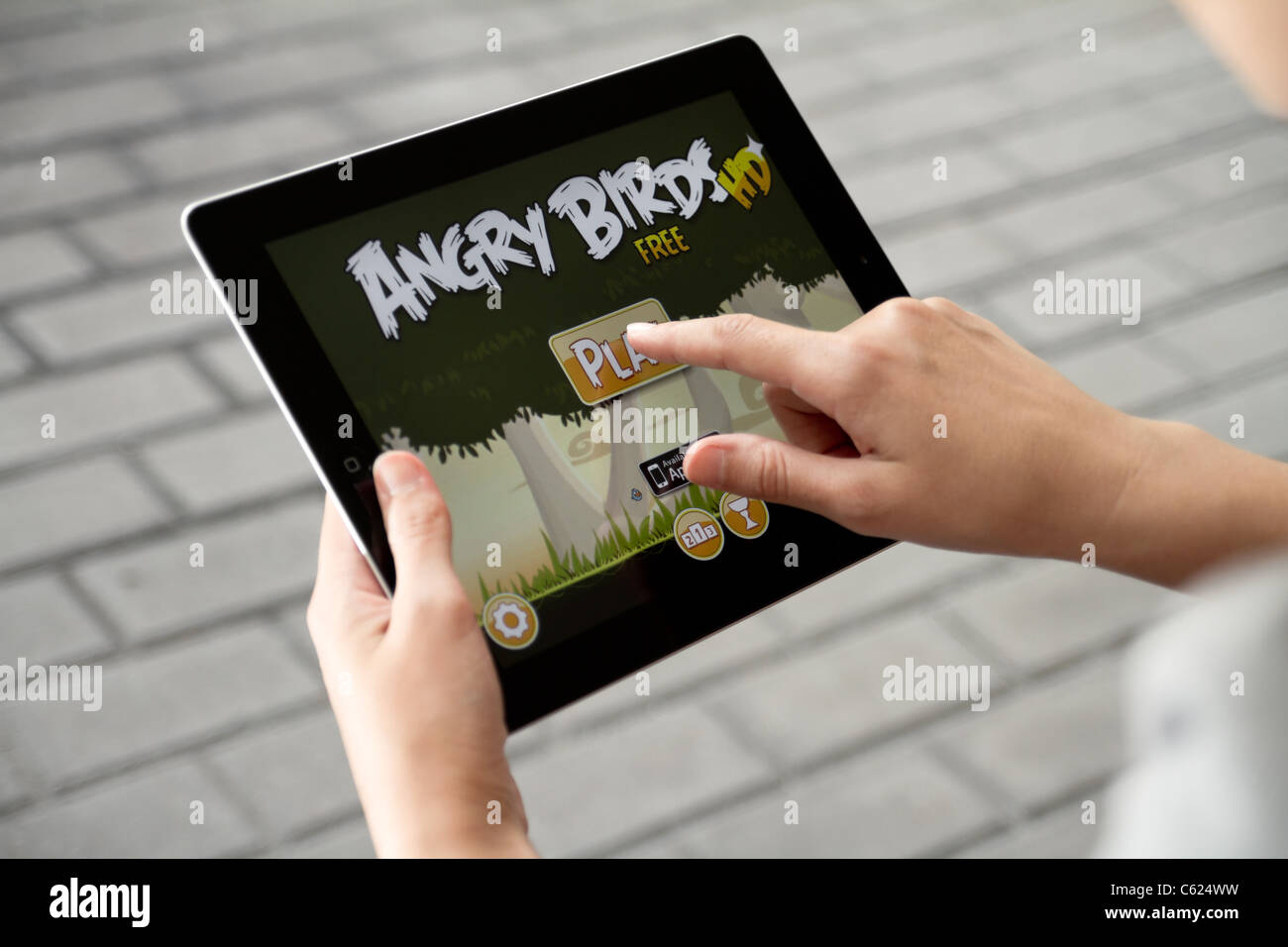 Une femme à l'extérieur jouer au jeu Angry Birds sur Apple ipad2 Banque D'Images