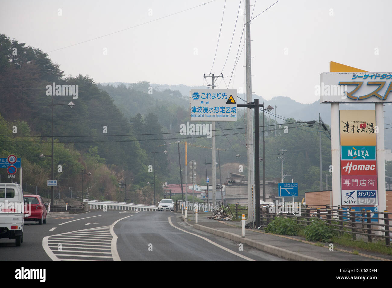 Un panneau placé avant le séisme avertit de la hauteur du tsunami prévu près de la chaussée endommagée près de Kamaishi - Iwate, Japon. Banque D'Images