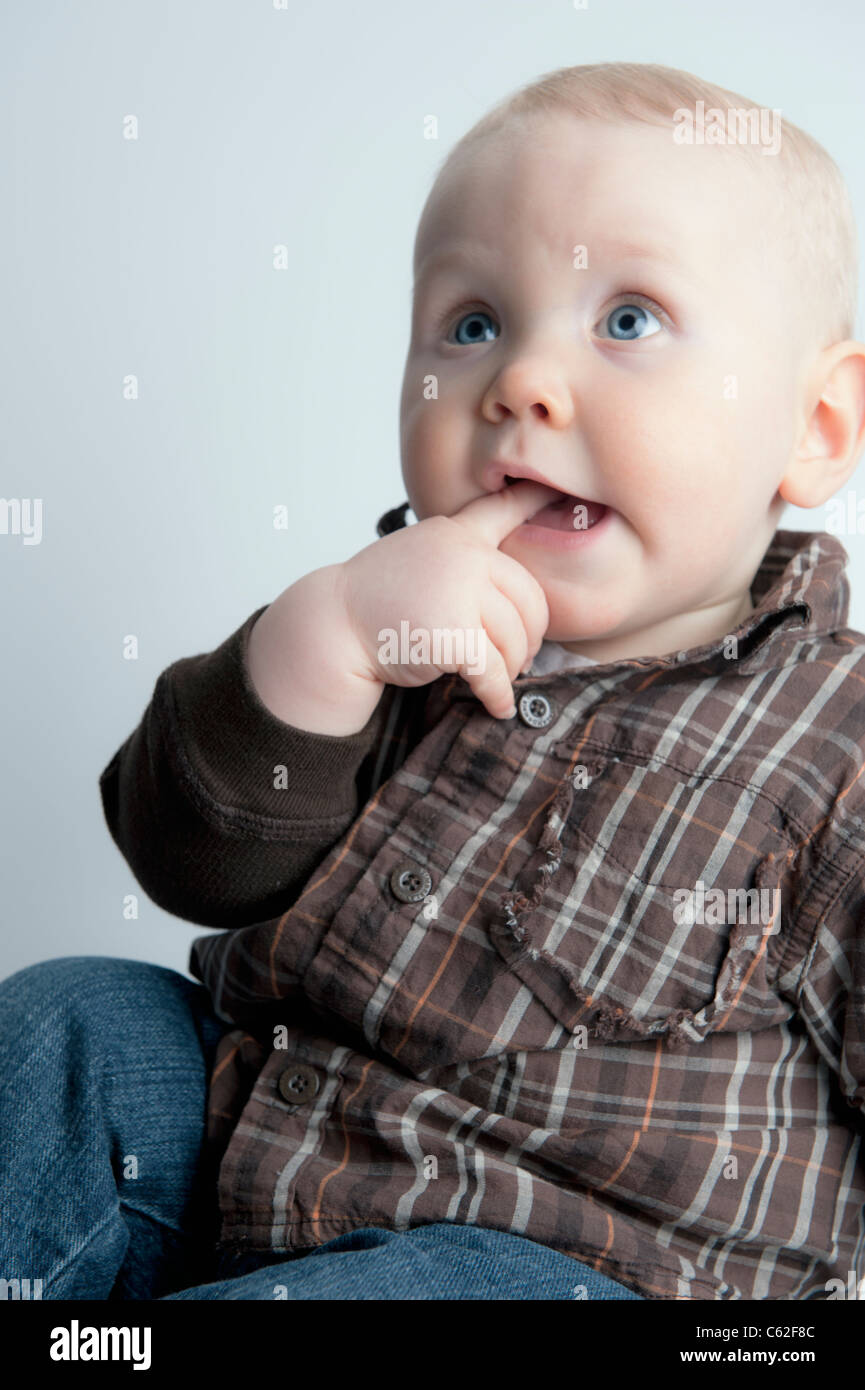 Un petit garçon de 9 mois, avec son doigt dans sa bouche Banque D'Images