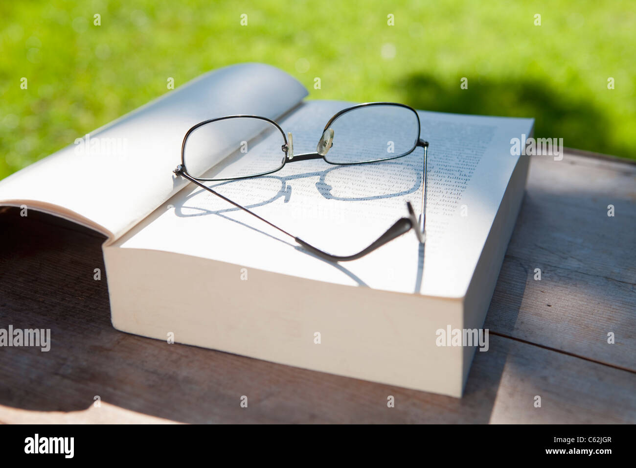 Libre de lunettes et un livre ouvert sur une table dans le jardin Banque D'Images