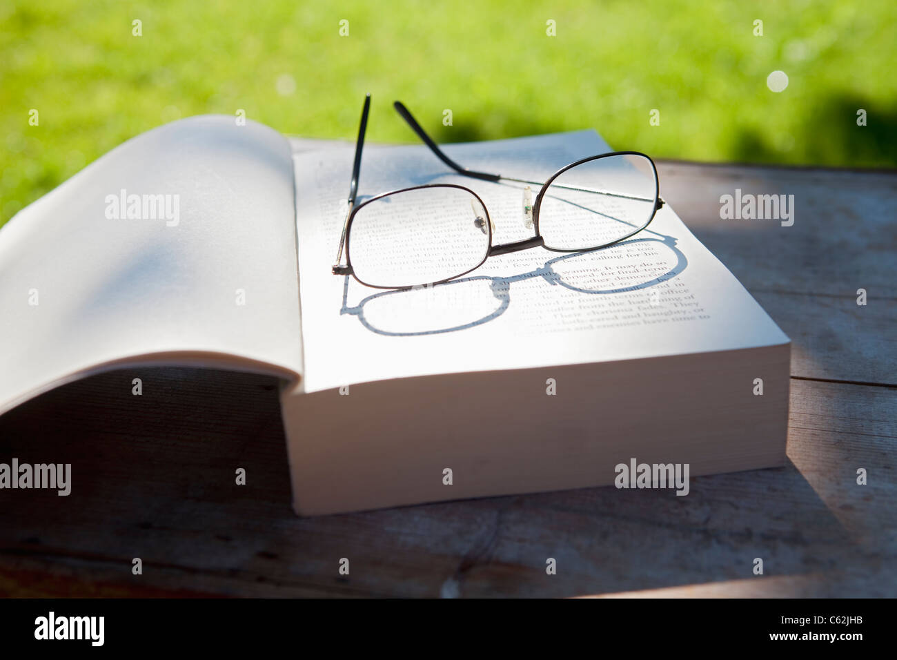 Libre de lunettes et un livre ouvert sur une table dans le jardin Banque D'Images